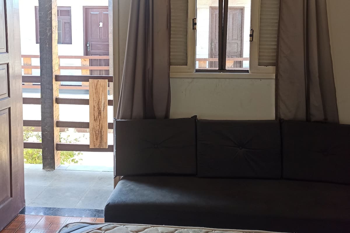 Une pièce comprenant un lit, un canapé, une fenêtre avec des rideaux et donnant sur l’extérieur.