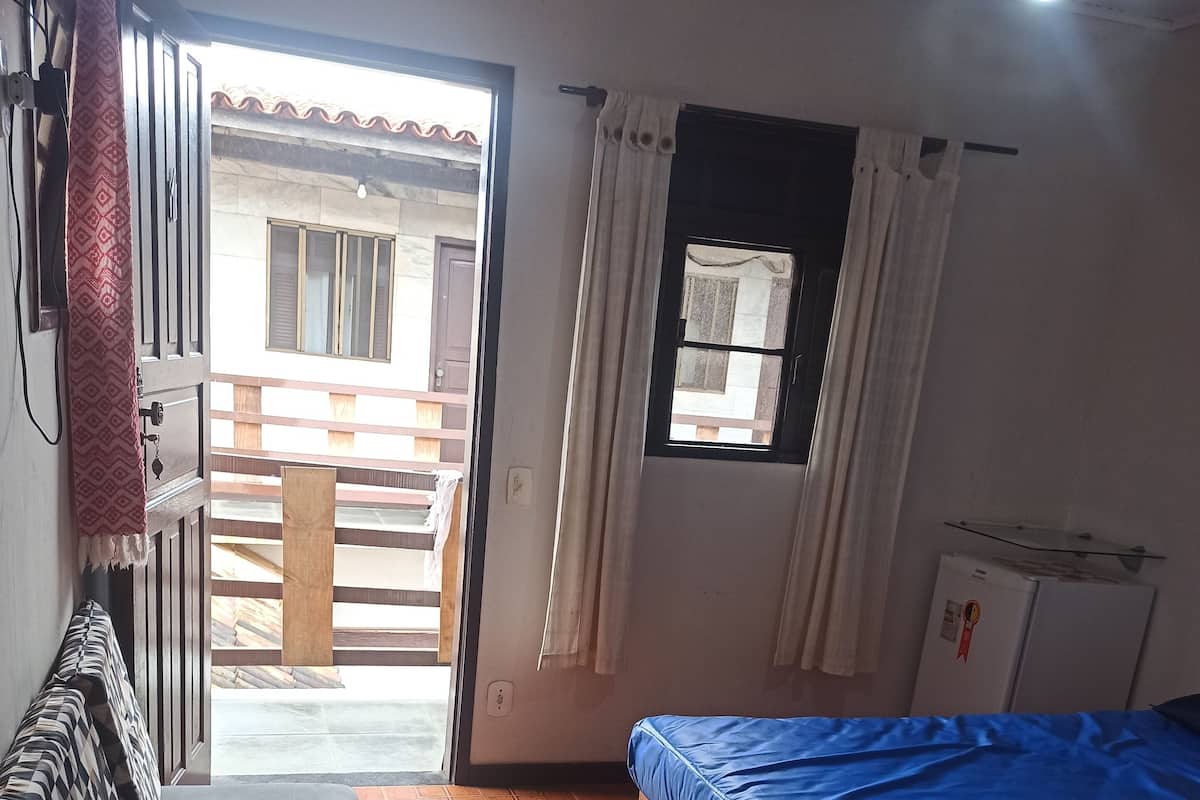 Une pièce comprenant un lit, un canapé, une fenêtre et une porte donnant sur l’extérieur.