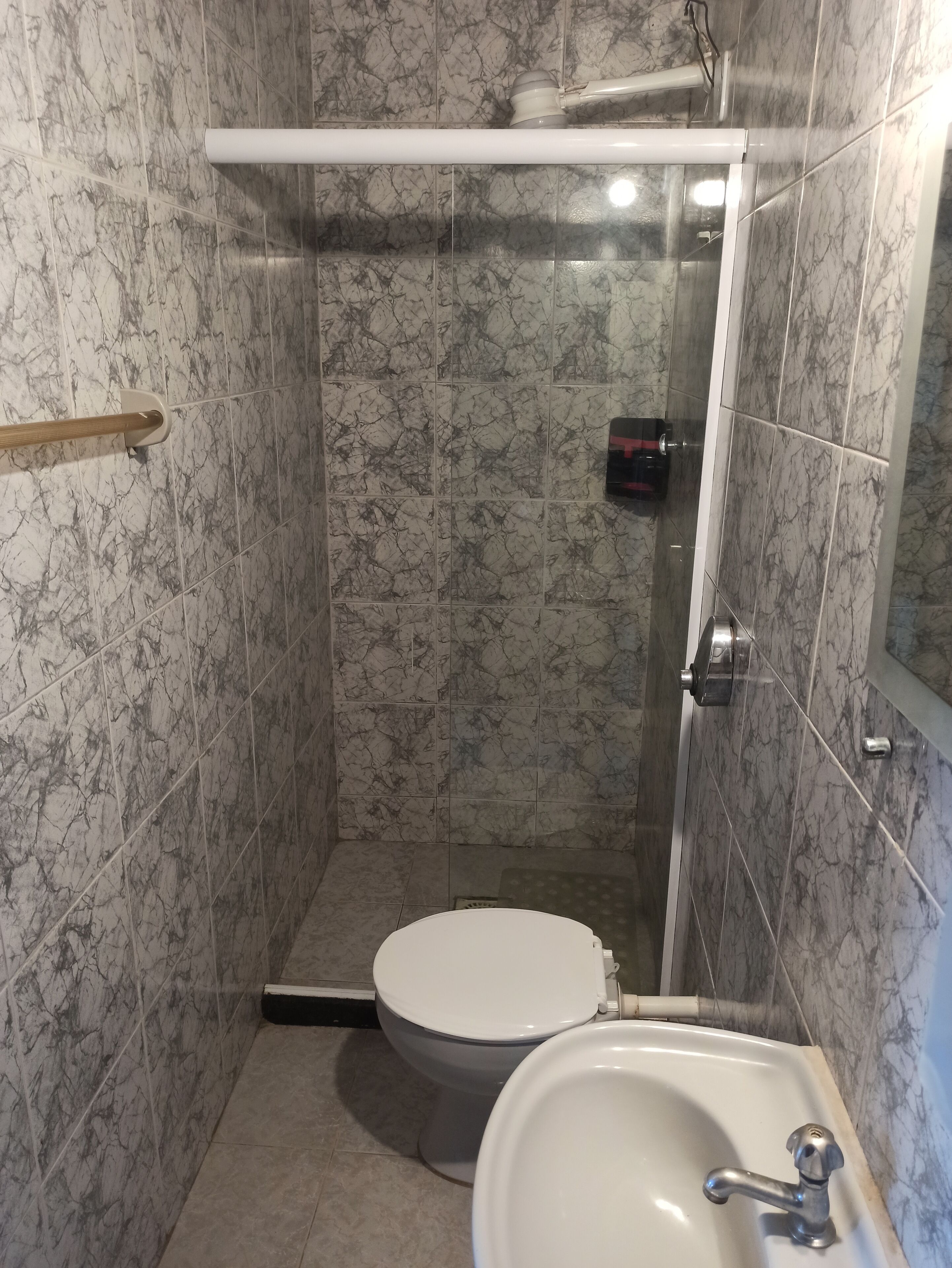 Ein Badezimmer mit Toilette, Waschbecken und Duschbereich.
