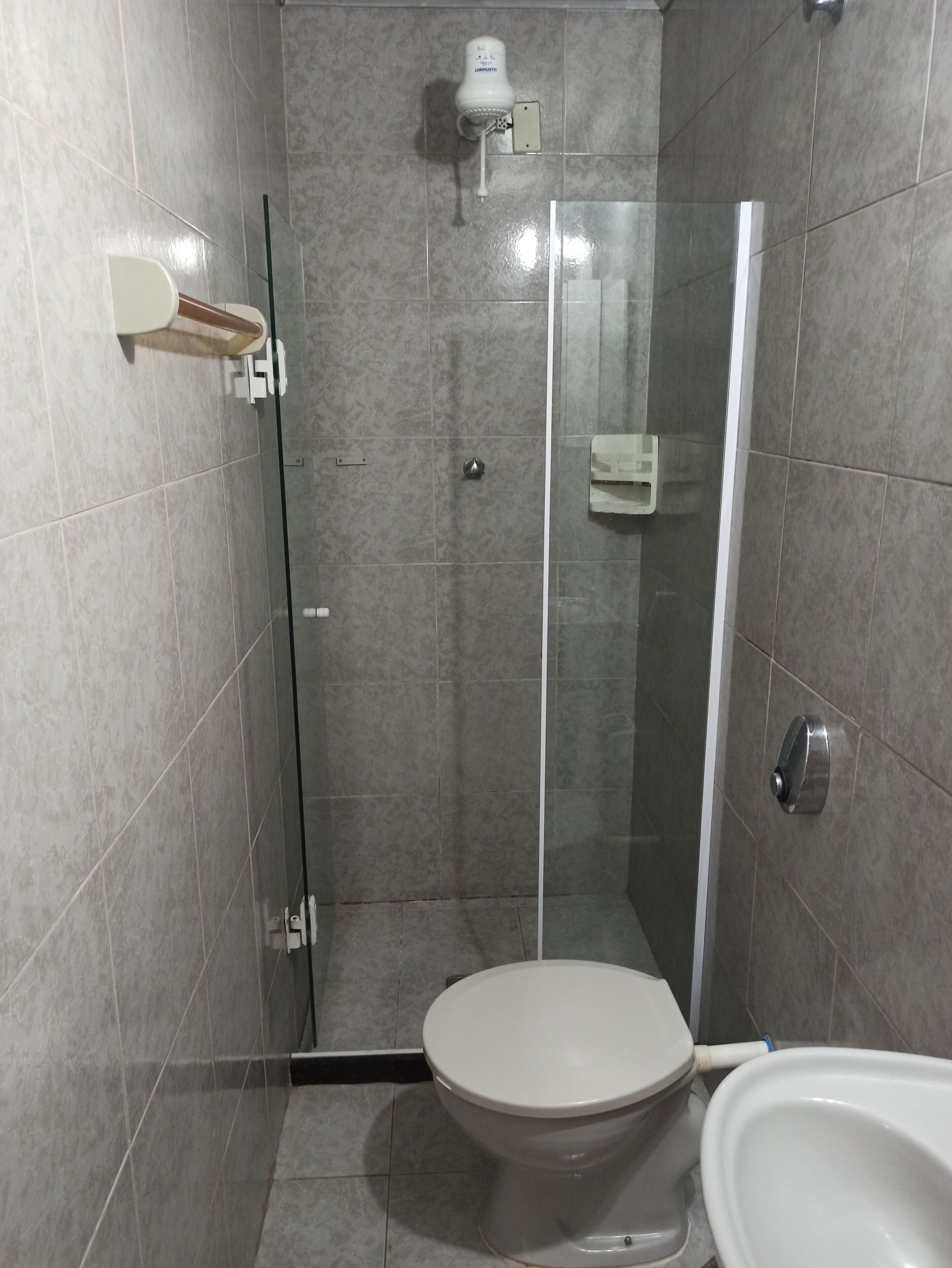 A modern bathroom with a glass-enclosed shower, a toilet, and a bidet.