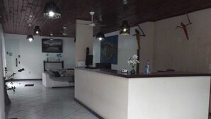 A spacious room with a reception desk, a sofa, and a dining table. - Buzios Geriba Aluguel Economico (Búzios)