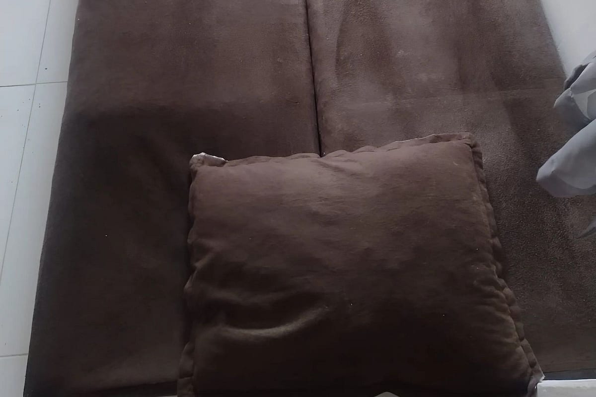Un grand rideau marron et un petit coussin marron sur un sol blanc.