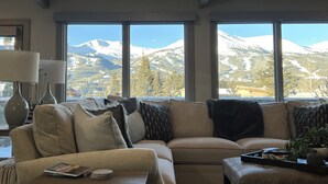 A living room with a large window offering a view of snow-capped mountains. -  Walk To Town, Ski In Style - Stunning Views w/Hot Tub, 1 block to Free Shuttle (Breckenridge)