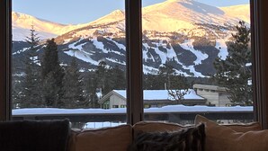 A view through a window of a mountain landscape with snow-covered slopes and a building in the foreground. -  Walk To Town, Ski In Style - Stunning Views w/Hot Tub, 1 block to Free Shuttle (Breckenridge)
