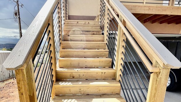 Un escalier en bois avec des rampes en métal menant à un niveau supérieur.