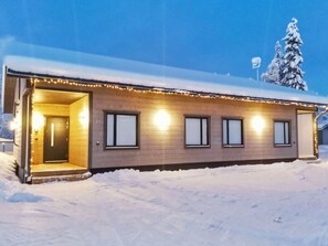 Um edifício térreo com entrada coberta e várias janelas, rodeado de neve.