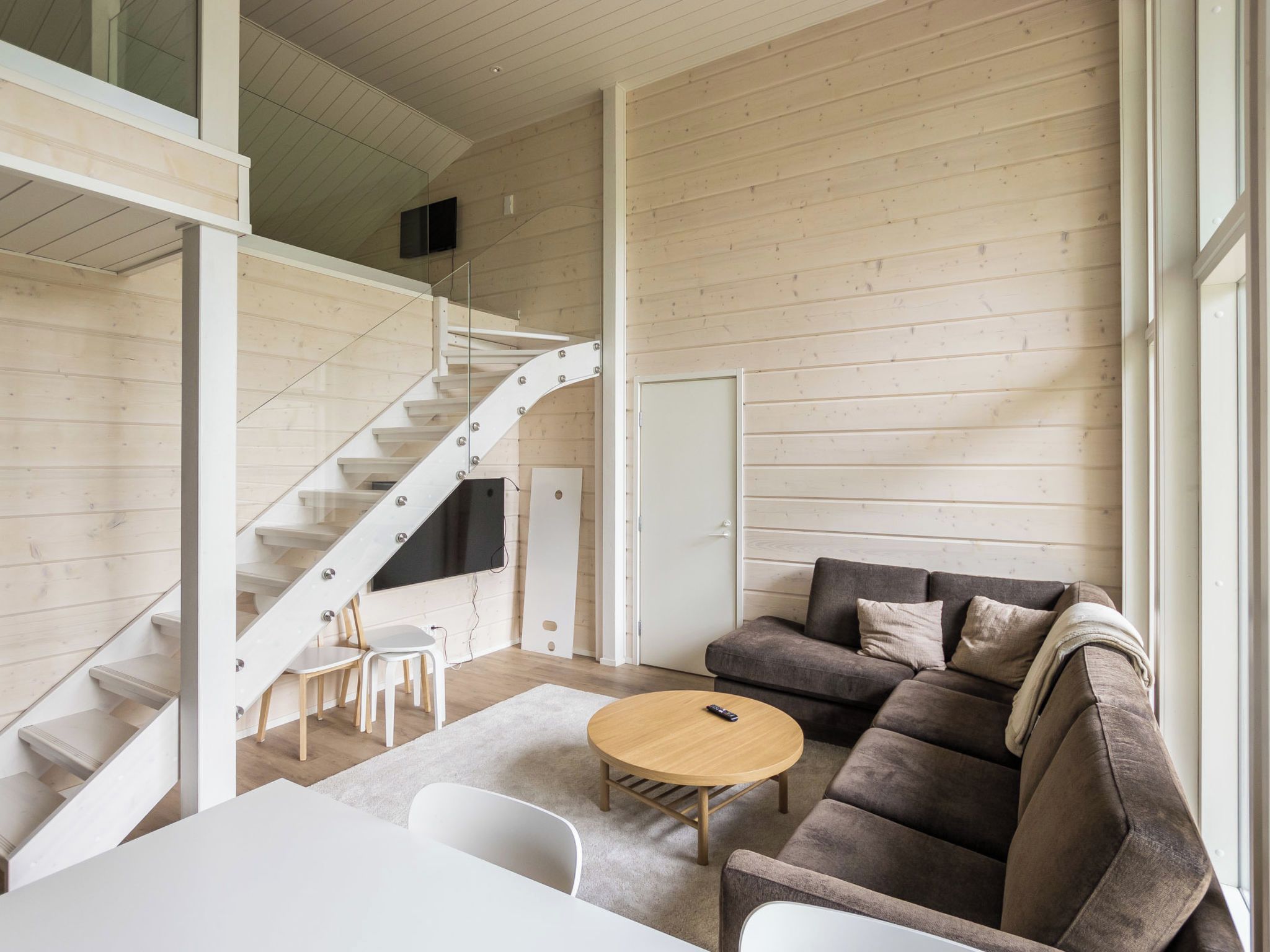 A modern interior with a staircase, a sofa, a table, and a TV.