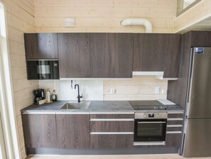 Una cocina moderna con armarios de madera oscura, un refrigerador de acero inoxidable, horno empotrado y microondas.