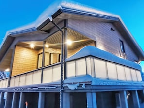 A two-story wooden house with a balcony, snow on the roof, and a clear sky. - Rikinänranta b by Interhome (Kittilä)