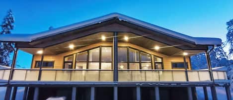 A modern building with a large glass facade, a covered porch area, and snow accumulation around the base.