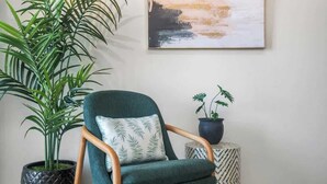 A room with a green armchair, a potted plant, and a small table with a patterned top. - Beautiful Queen Penthouse with Large Terrace (San Juan)