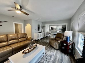 A living room with a brown leather sofa, a white coffee table, and a ceiling fan.