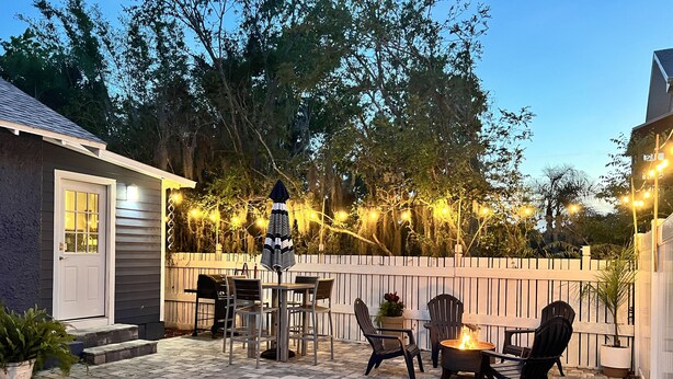 Un patio con un brasero, mobiliario exterior e iluminación con luces colgantes.