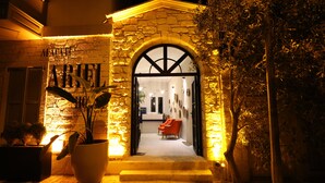 A stone building with a large arched entrance, potted plants, and a red chair inside. - Ariel Hotel Alaçatı (Cesme)