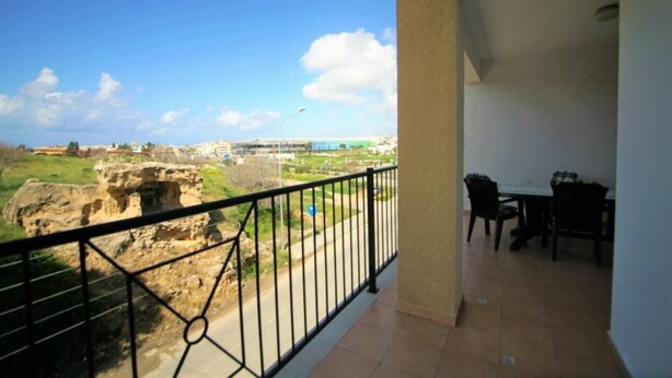 A balcony with a view of a cityscape, including buildings and a body of water. - Beautiful Apartment With Pool in Paphos, Cyprus (Paphos)