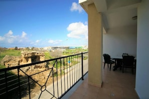 A balcony with a view of a cityscape, including buildings and a body of water.