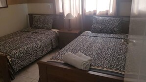 A hotel room with two beds, each with a leopard print bedspread. There is a nightstand with a lamp between the beds, and a window with curtains. - Beautiful Apartment With Pool in Paphos, Cyprus (Paphos)