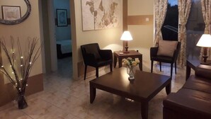 A cozy living room with a coffee table, two armchairs, a lamp, and a vase of flowers. - Beautiful Apartment With Pool in Paphos, Cyprus (Paphos)