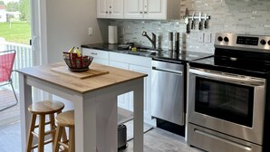 Une cuisine moderne avec des armoires blanches, une cuisinière en acier inoxydable et un dosseret carrelé.