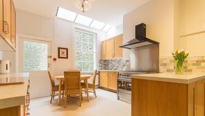 A modern kitchen with a dining area, large windows, and a central island. - 98 Fountain Villas - sleeps 16 guests  in 7 bedrooms (Matlock Bath)
