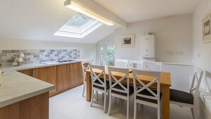 A modern kitchen with a skylight, white cabinets, a dining table with chairs, and a view of the outdoors. - 98 Fountain Villas - sleeps 16 guests  in 7 bedrooms (Matlock Bath)