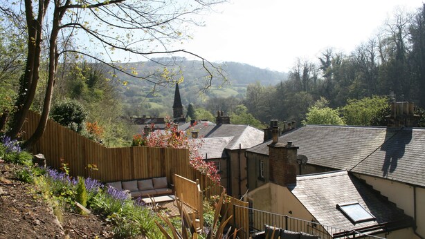 A residential area with a garden, a wooden fence, and a view of a church spire in the distance. - 98 Fountain Villas - sleeps 16 guests  in 7 bedrooms (Matlock Bath)