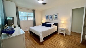 Une chambre d’hôtel avec un lit, des tables de chevet, un bureau et une fenêtre avec des rideaux.