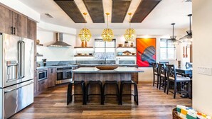 A modern kitchen with a central island, stainless steel appliances, and pendant lighting. - Polynesian Villa w/Private Pool & Tiki Bar Oasis (Indio)