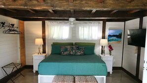 A bedroom with a large bed, two bedside tables, a TV, and a ceiling fan. - Island Escape for Two, Class and Comfort (Coral Bay Quarter)