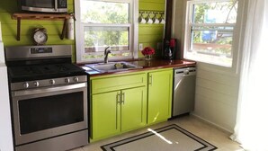 A kitchen with a stove, microwave, sink, and green cabinets. - Island Escape for Two, Class and Comfort (Coral Bay Quarter)