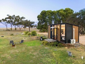 A compact, single-story structure with an open entrance, a small porch, and a grill area. - Avondale Heights by Tiny Away (Banyena)