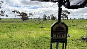 A portable barbecue grill in a grassy field with trees and a cloudy sky in the background. - Avondale Heights by Tiny Away (Banyena)