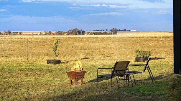 An outdoor seating area with a fire pit and chairs, overlooking a vast field. - Avondale Heights by Tiny Away (Banyena)