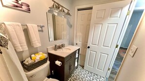 A bathroom with a toilet, sink, and vanity. There is a patterned floor and a door in the background. - 2 br home close to downtown and Lucas Oil. Pet Friendly! (Indianapolis)