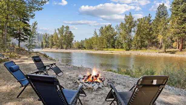 A riverside campsite with a fire pit and four lounge chairs. - Riverfront 4 bed/3bath home on Bitterroot River plus a Pickleball Court  (Hamilton)
