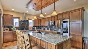 Ett rymligt kök med träskåp, bänkskivor i granit och vitvaror i rostfritt stål.