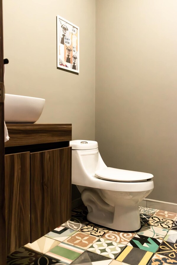 Un baño con inodoro, mueble de madera y lavamanos.