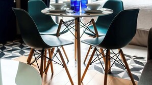 Moderni hotellihuone, jossa on suuri ikkuna, ruokapöytä tuoleineen, sänky ja vaatekaappi.