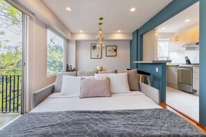 Une chambre moderne dotée d’un grand lit, d’un balcon et d’un coin cuisine.