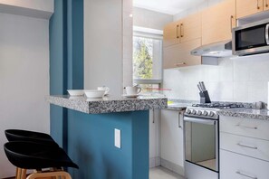 A modern kitchen with granite countertops, a gas stove, a microwave, and wooden cabinets.