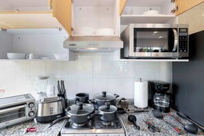 Une cuisine équipée d’une cuisinière, d’un four à micro-ondes, d’un grille-pain, de casseroles et d’une machine à café.