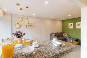 A modern kitchen with granite countertops, hanging pendant lights, and a dining area with a table set for four.