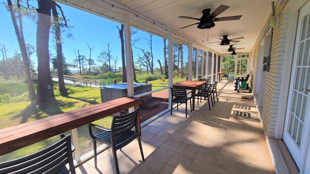 A covered patio with outdoor seating, a barbecue grill, and a view of the surrounding trees. - Ground Level, Bayside Retreat w/ bay access! Dogs OK, Large Pond (Eastpoint)