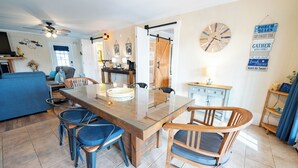 A dining area with a glass-top table, wooden chairs, and a kitchen in the background. - Ground Level, Bayside Retreat w/ bay access! Dogs OK, Large Pond (Eastpoint)