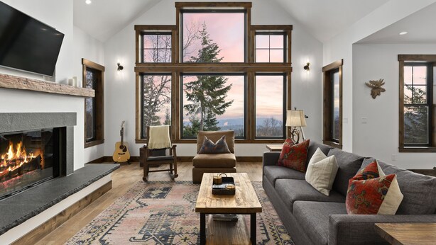 A spacious living room with a fireplace, large windows, a sofa, and a coffee table.