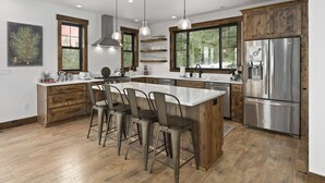 A modern kitchen with a large island, stainless steel appliances, and wooden cabinetry.