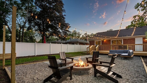 A backyard with a fire pit, outdoor seating, and string lights.