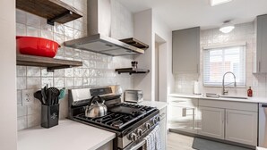 A modern kitchen with a stainless steel stove, a toaster, and a red pot on a shelf.