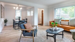 A modern living room with a sofa, coffee table, and dining area.