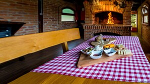 A restaurant interior with a brick wall, a brick fireplace, a wooden bench, and a table with a red and white checkered tablecloth. - Holiday House Papuk is Located in Park of Nature (Brestovac)